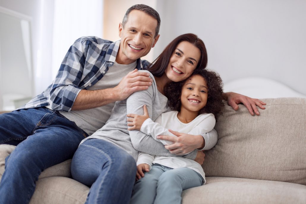 Foster child sitting on couch with her foster parents