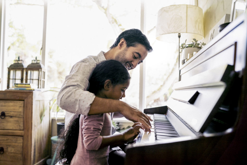 Man teaching his foster child to play piano after considering questions to ask before receiving his foster placement