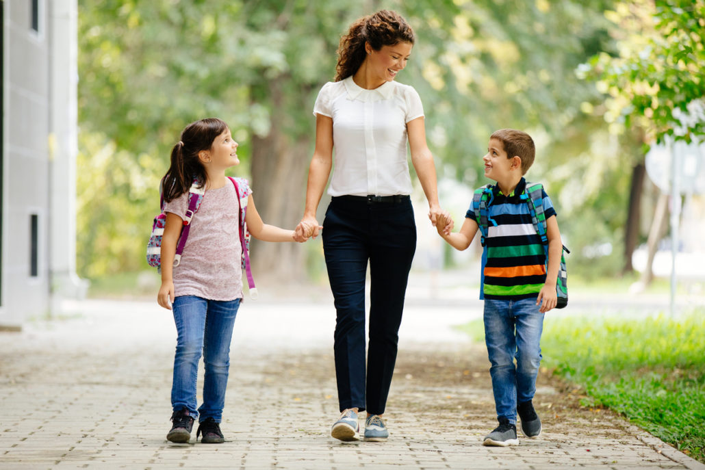 Woman walking her foster children to school, showcasing the reality of fostering a child