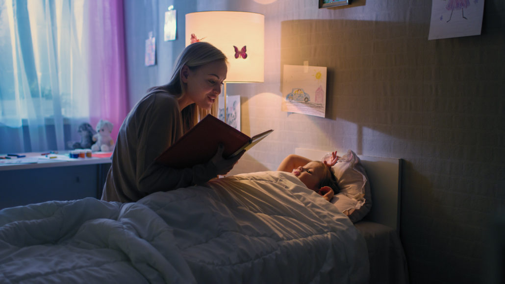 tucking a child into their own bed with a bedtime story